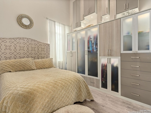 bedroom featuring light hardwood / wood-style floors and a high ceiling