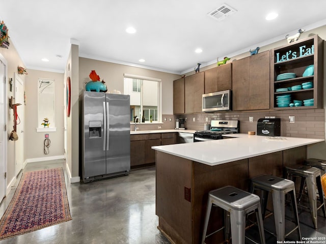 kitchen featuring appliances with stainless steel finishes, a kitchen breakfast bar, decorative backsplash, dark brown cabinetry, and kitchen peninsula