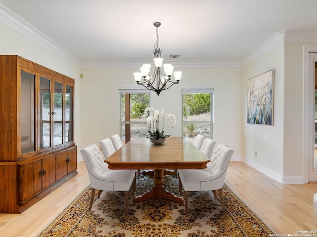 dining space featuring ornamental molding, an inviting chandelier, and light wood-type flooring