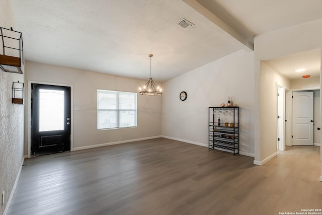 entrance foyer featuring vaulted ceiling with beams, hardwood / wood-style floors, and a chandelier