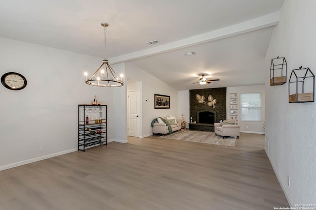 unfurnished living room featuring lofted ceiling with beams, wood-type flooring, ceiling fan with notable chandelier, and a fireplace