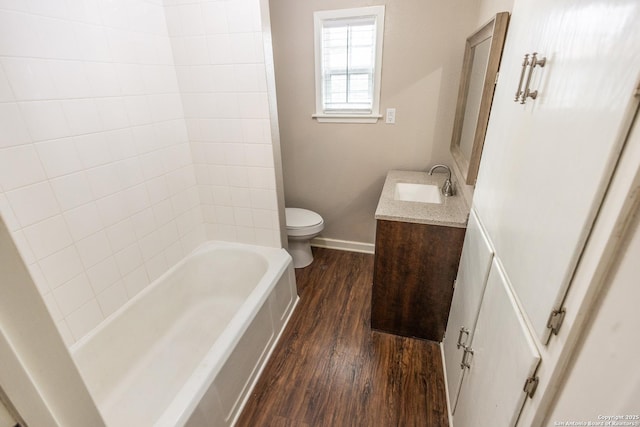 full bathroom with vanity, hardwood / wood-style floors, tiled shower / bath combo, and toilet