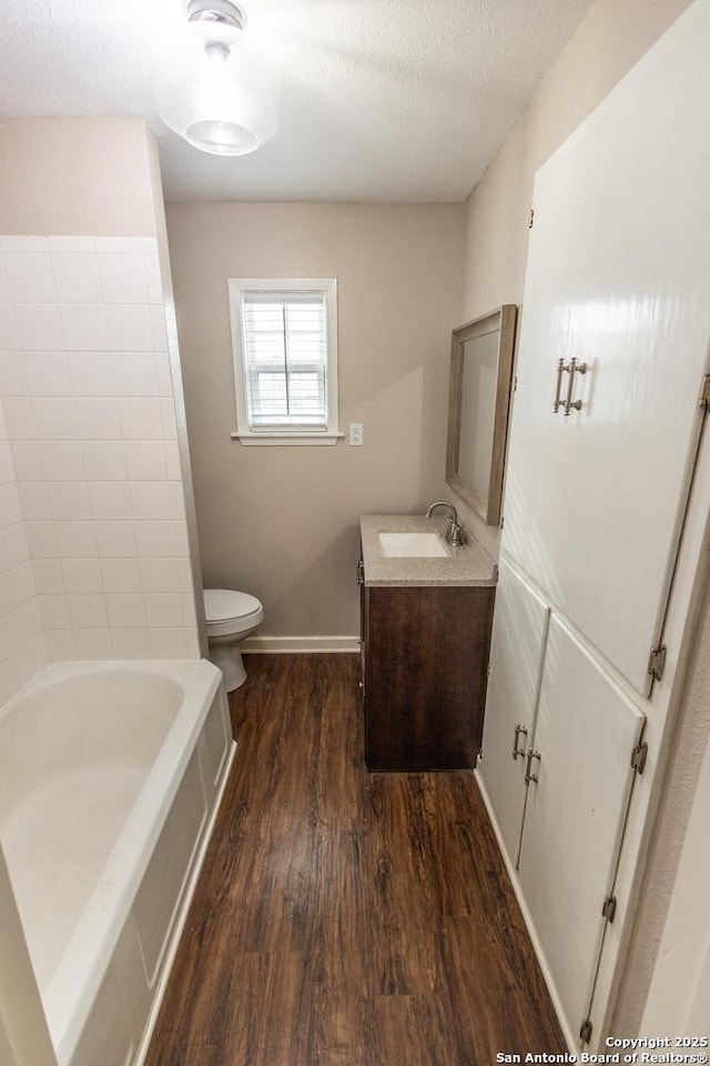 bathroom featuring hardwood / wood-style flooring, vanity, toilet, and a textured ceiling