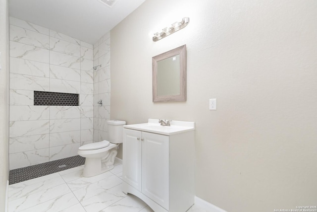 bathroom featuring vanity, tiled shower, and toilet