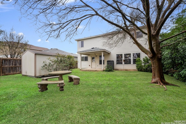 rear view of property with central AC and a yard