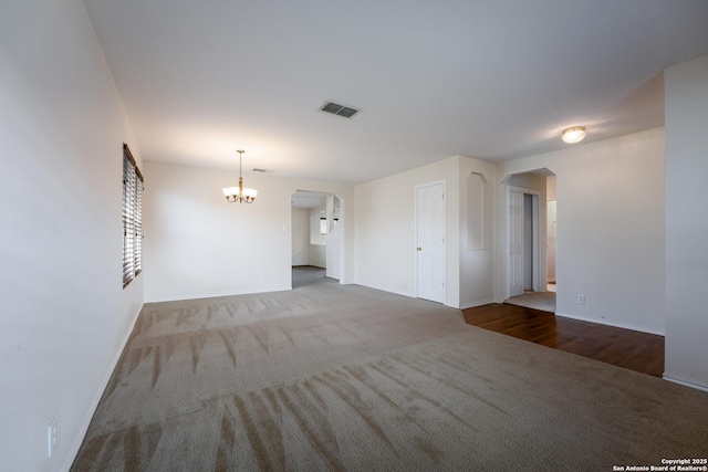 unfurnished living room featuring an inviting chandelier and carpet floors