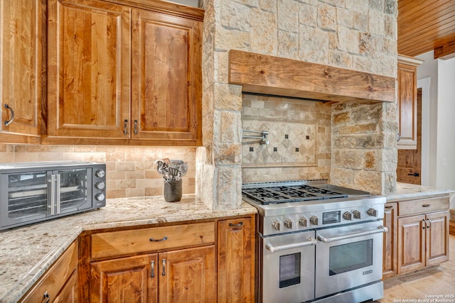 kitchen featuring light stone counters, wood ceiling, double oven range, and tasteful backsplash