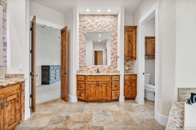 bathroom with vanity, toilet, and backsplash