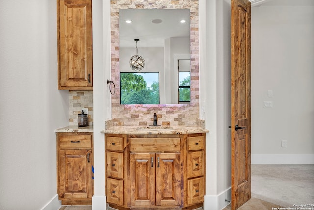 bar with light stone counters, hanging light fixtures, backsplash, and sink