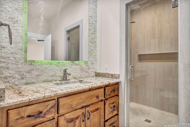 bathroom featuring vanity, a shower with shower door, and decorative backsplash