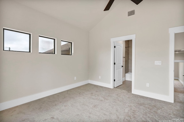 unfurnished bedroom featuring high vaulted ceiling, light colored carpet, and ensuite bathroom