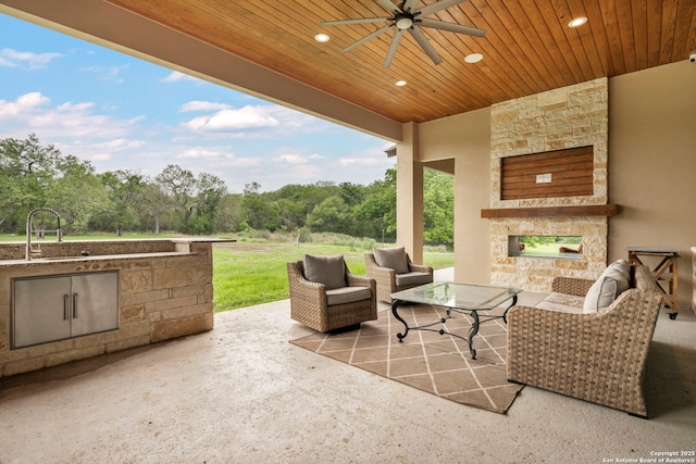 view of patio / terrace featuring an outdoor living space with a fireplace, sink, and ceiling fan