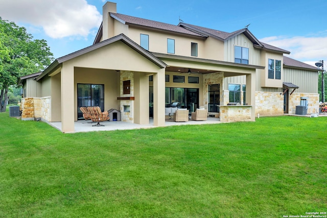 back of property featuring a lawn, an outdoor living space with a fireplace, ceiling fan, central air condition unit, and a patio area