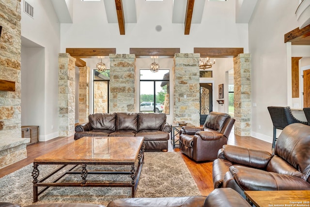 living room with beamed ceiling, wood-type flooring, decorative columns, and a high ceiling