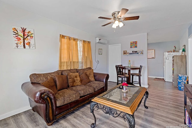 living room featuring ceiling fan, hardwood / wood-style floors, and an AC wall unit