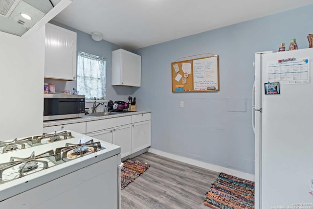 kitchen with white appliances, sink, light hardwood / wood-style flooring, and white cabinets