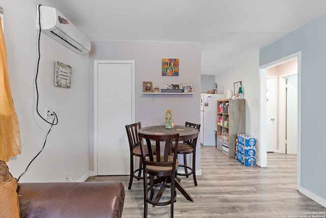 dining room featuring a wall mounted air conditioner and light hardwood / wood-style floors