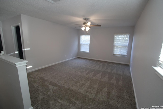 spare room with ceiling fan, dark carpet, and a textured ceiling