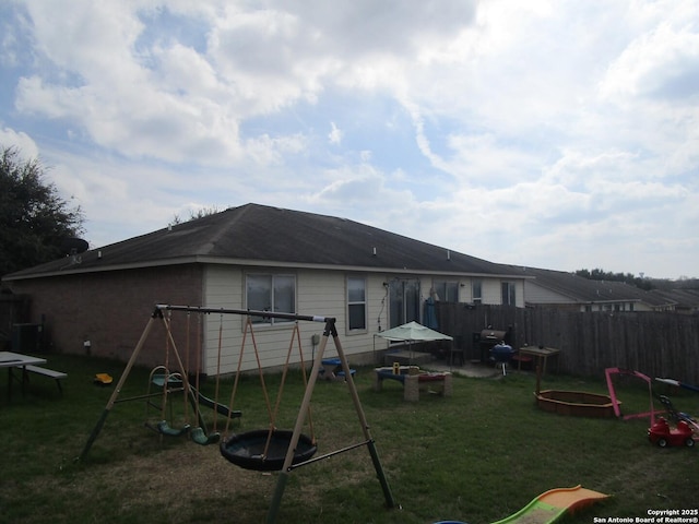 back of property with a yard and a playground