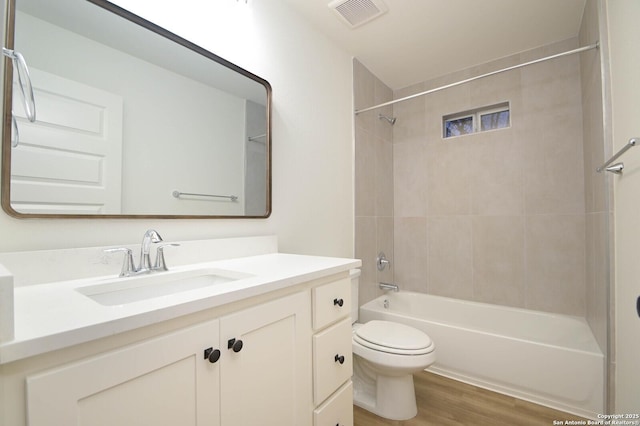 full bathroom with vanity, hardwood / wood-style flooring, tiled shower / bath combo, and toilet