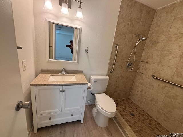 bathroom with vanity, toilet, wood-type flooring, and a tile shower