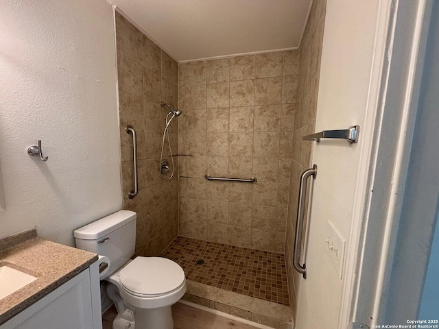 bathroom with vanity, toilet, and a tile shower