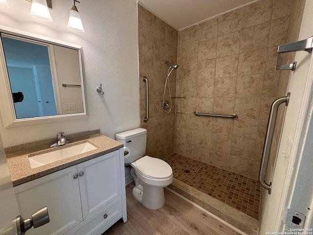 bathroom with vanity, hardwood / wood-style flooring, toilet, and a tile shower