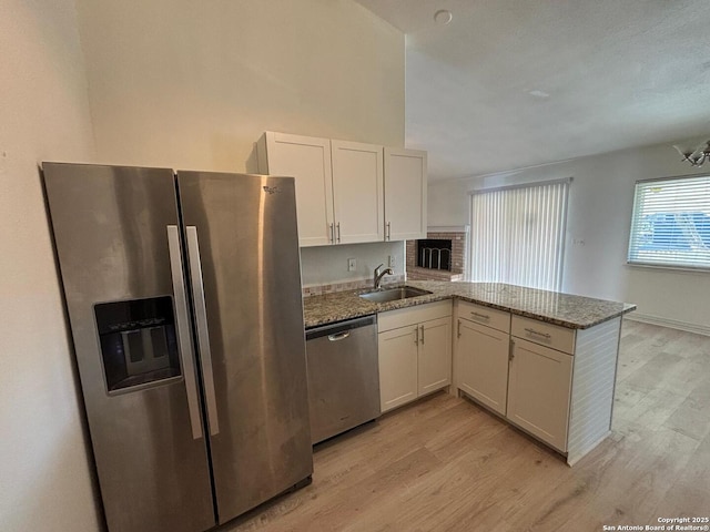 kitchen featuring stainless steel appliances, white cabinetry, sink, and kitchen peninsula