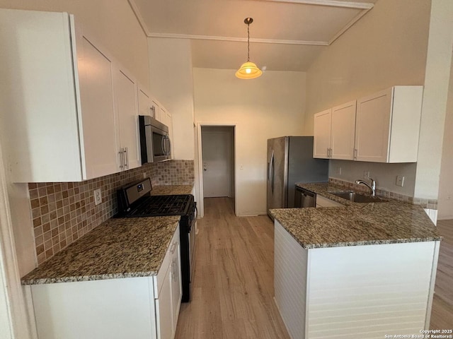 kitchen with appliances with stainless steel finishes, pendant lighting, sink, dark stone countertops, and white cabinets