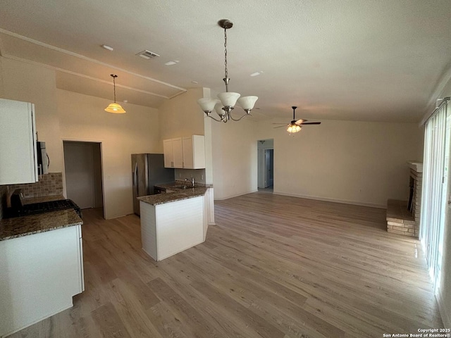 kitchen featuring sink, decorative light fixtures, vaulted ceiling, light hardwood / wood-style flooring, and white cabinets