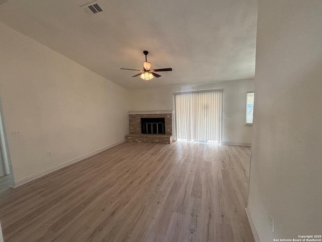 unfurnished living room featuring a brick fireplace, ceiling fan, and light wood-type flooring