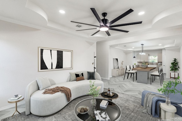 living room with a tray ceiling, light parquet flooring, and ceiling fan