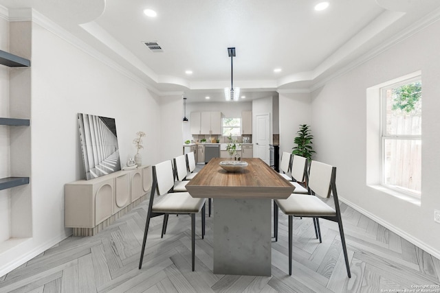 dining area with a tray ceiling, light parquet flooring, and crown molding