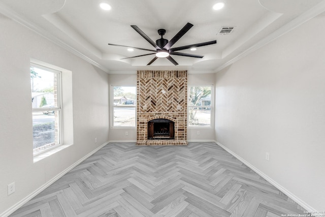 unfurnished living room with a raised ceiling, plenty of natural light, and a brick fireplace