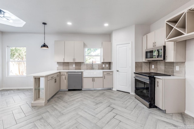 kitchen with sink, a skylight, stainless steel appliances, white cabinets, and hanging light fixtures