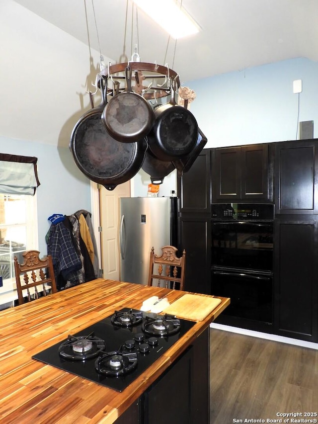 kitchen featuring wood counters, dark wood-type flooring, black appliances, and lofted ceiling