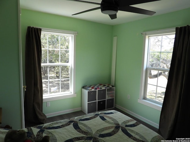 bedroom with multiple windows, wood-type flooring, and ceiling fan