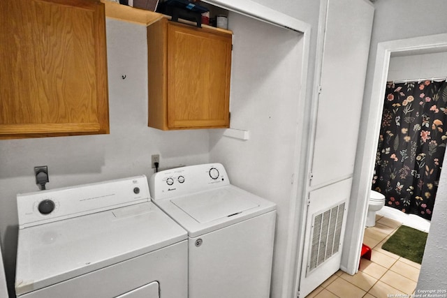 washroom featuring cabinets, washer and dryer, and light tile patterned flooring