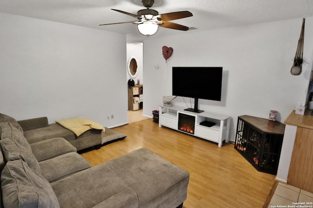 living room with hardwood / wood-style flooring, ceiling fan, and a textured ceiling