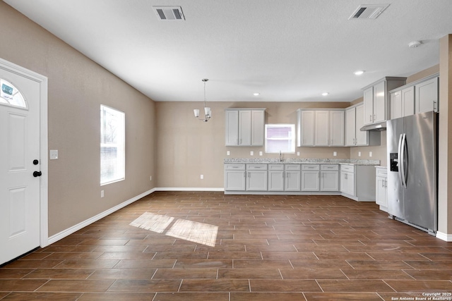 4423 Buena Vista St, San Antonio, TX 78237 - kitchen featuring sink, white cabinetry, light stone counters, decorative light fixtures, and stainless steel fridge