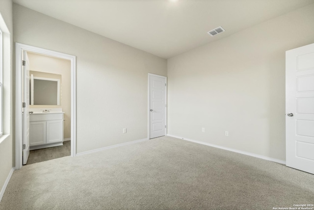 unfurnished bedroom featuring connected bathroom and light colored carpet