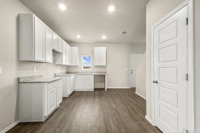 kitchen featuring light stone countertops, dark wood-type flooring, sink, and white cabinets