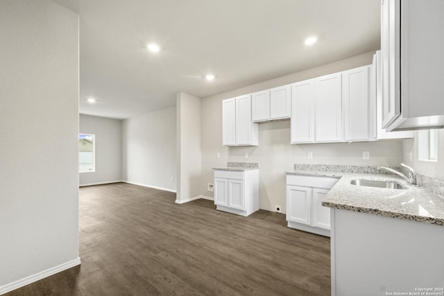 kitchen featuring light stone counters, dark wood-type flooring, sink, and white cabinets