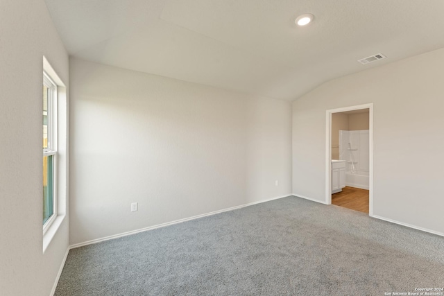 carpeted empty room featuring lofted ceiling