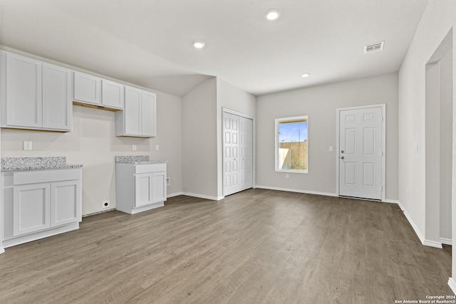 kitchen with light stone countertops, white cabinets, and light hardwood / wood-style floors