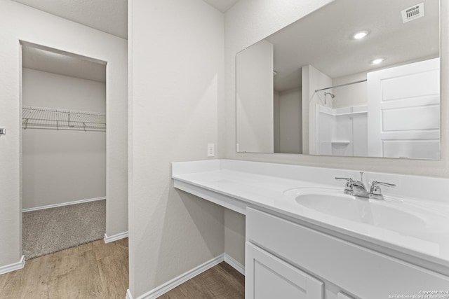 bathroom featuring vanity, wood-type flooring, and walk in shower
