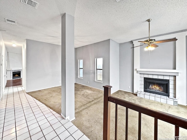 unfurnished living room with ceiling fan, light colored carpet, a textured ceiling, and a fireplace