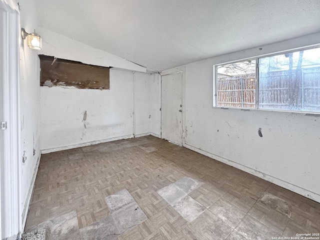 unfurnished room featuring light parquet flooring, lofted ceiling, and a textured ceiling