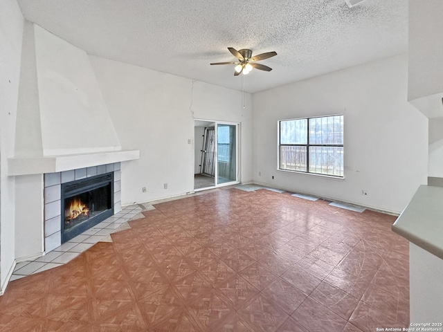 unfurnished living room with a textured ceiling, a tile fireplace, and ceiling fan