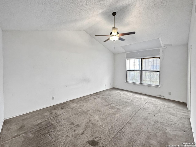 carpeted empty room featuring vaulted ceiling, a textured ceiling, and ceiling fan